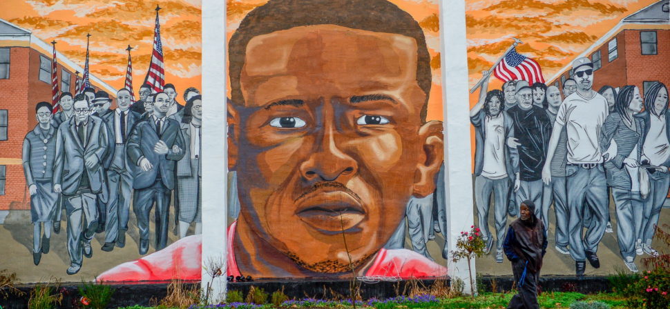 A man, who declined to offer his name, walks past a mural of Freddie Gray in the Sandtown-Winchester neighborhood of Baltimore, December 17, 2015. On Wednesday, Judge Barry Williams declared a mistrial in the case of Police Officer William Porter, one of six officer charged connection with the death of Freddie Gray. REUTERS/Bryan Woolston EDITORIAL USE ONLY. NO RESALES. NO ARCHIVE - RTX1Z4YV